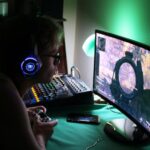 A person sitting at their desktop and playing a video game.