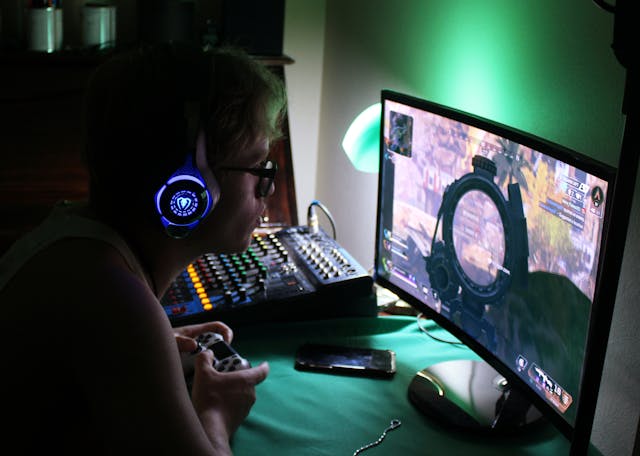 A person sitting at their desktop and playing a video game.